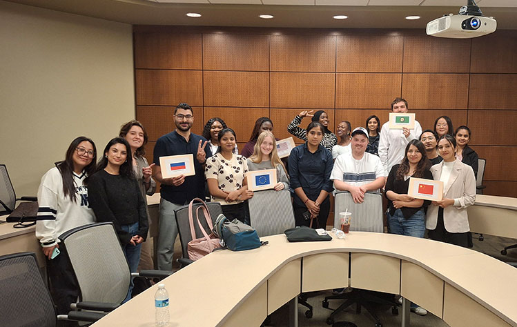 Students pose with print out of flags from around the world that were used in the simulated diplomatic environment training. 