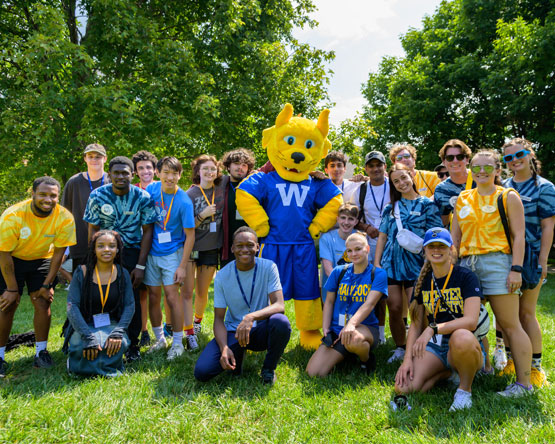The Webster Gorlok mascot posing for a photo with a group of Webster students.