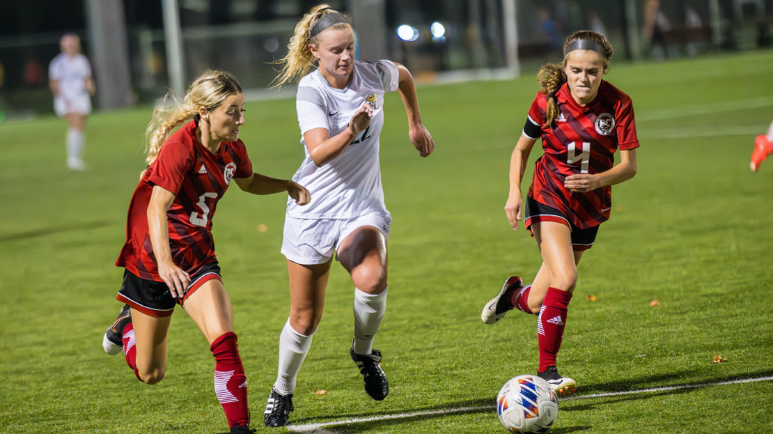 A female student races for a soccer ball