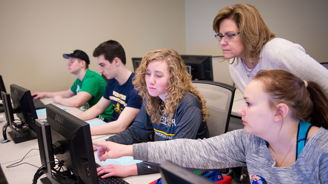 A group of students asking a professor a computer question.