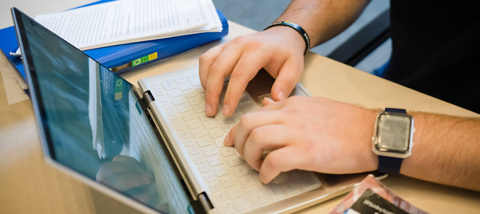 A close up of a pair of hands typing on a laptop.