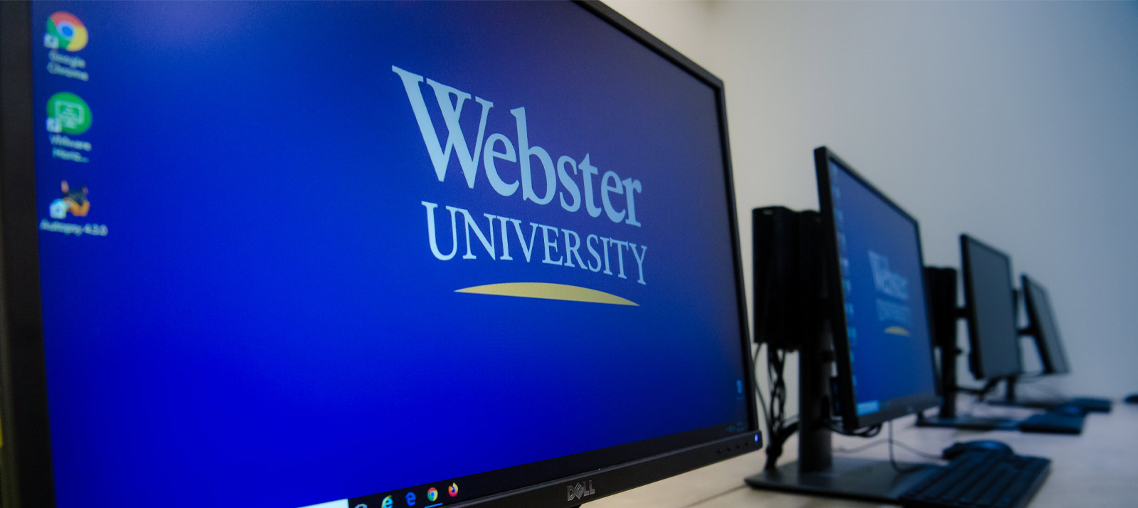 A desktop computer with a Webster University background.