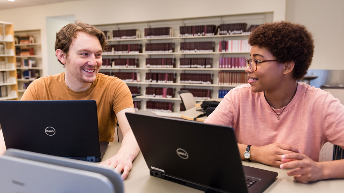A pair of students working on laptops.