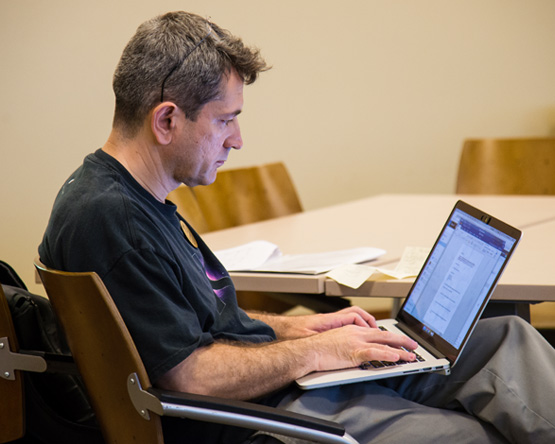 Seated student types on laptop that sits on his legs