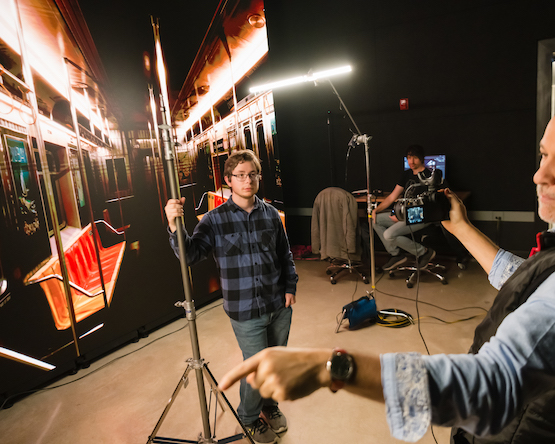 A student posing against a backdrop for a film class.