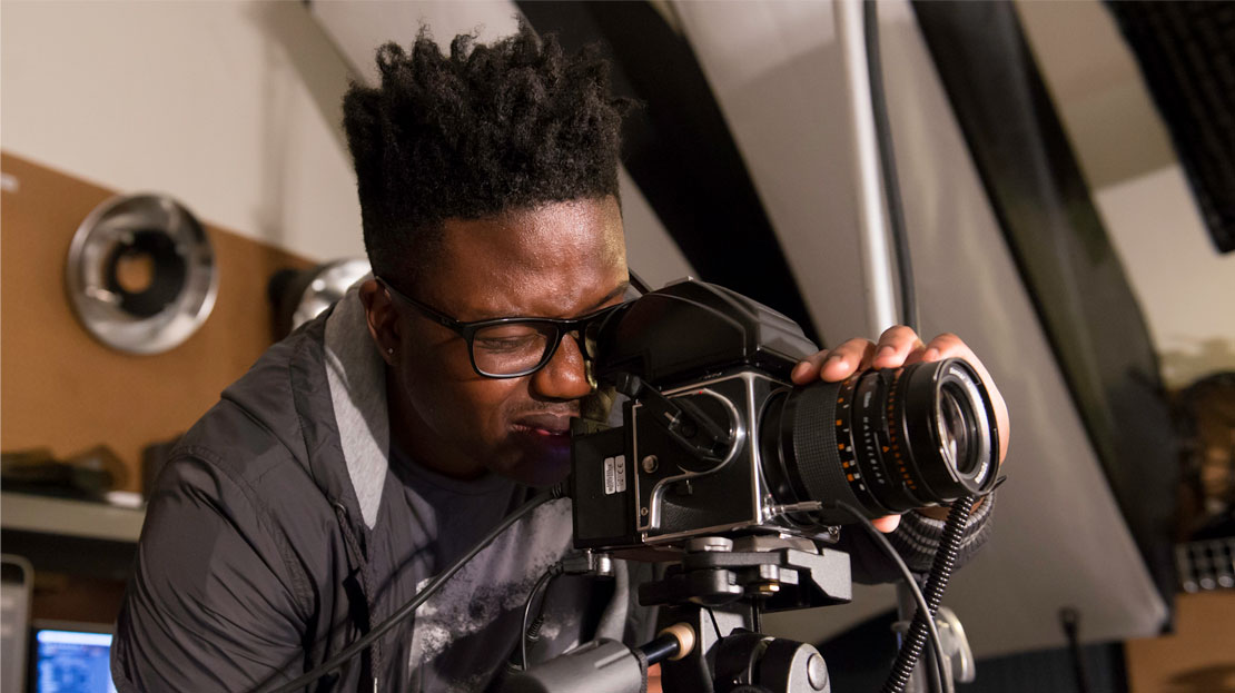A Webster student operates a camera in a photography studio.