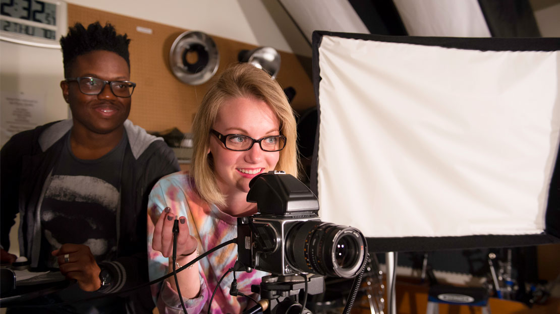 Webster students working with a camera in a photography studio.