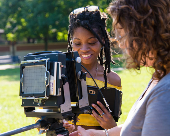 A Webster student recieves instruction in an outdoor photography lesson.