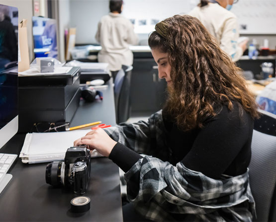 Student working at desk next to camera.