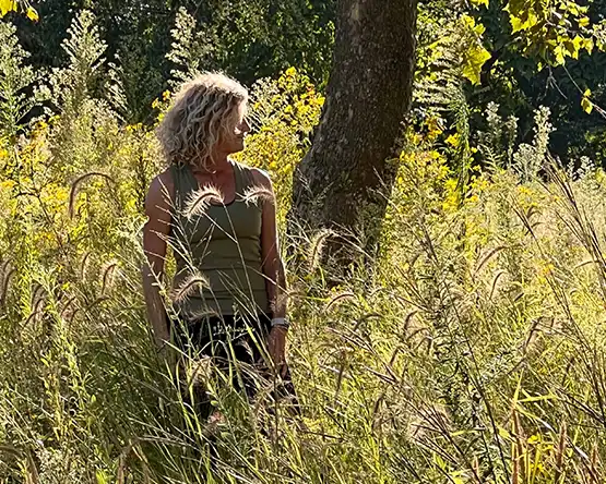 Lisa Halley Meching stands in a field of yellow near a tree