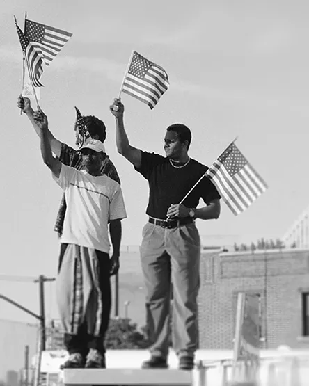 Three men standing on top of a building waving American flags