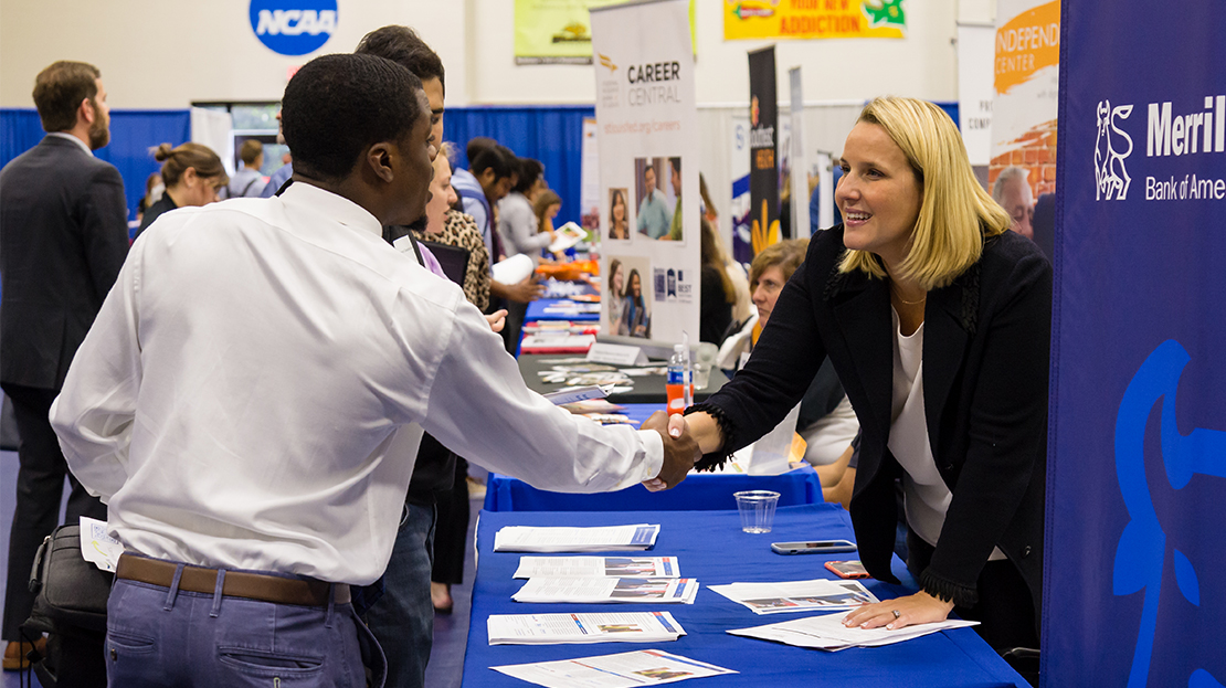 A Webster student exchanging a handshake at a career fair.