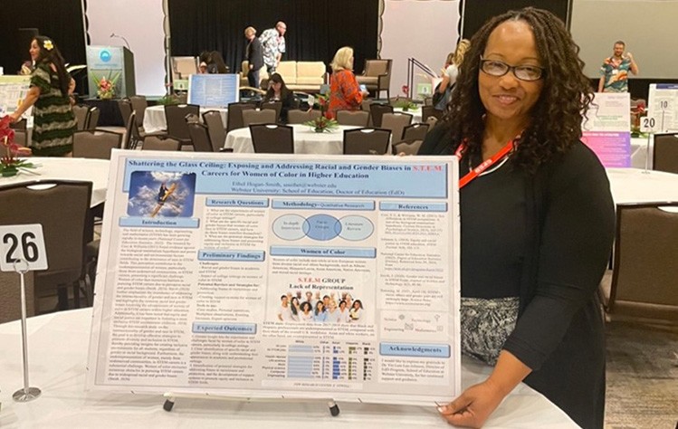 Ethyl Smith holds the edges of her poster presentation in a conference ballroom