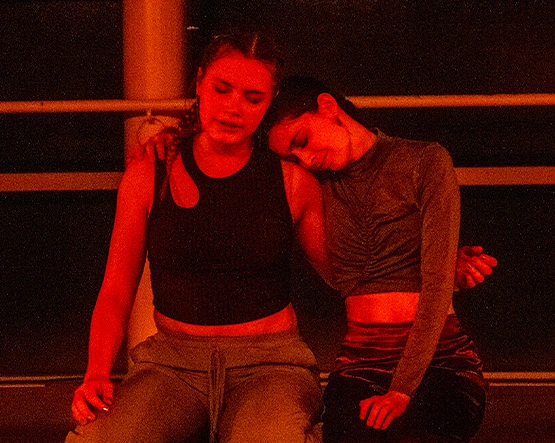 Two dancers perform while bathed in red light.