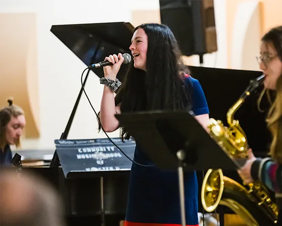 Music student singing accompanied by saxophone and piano.