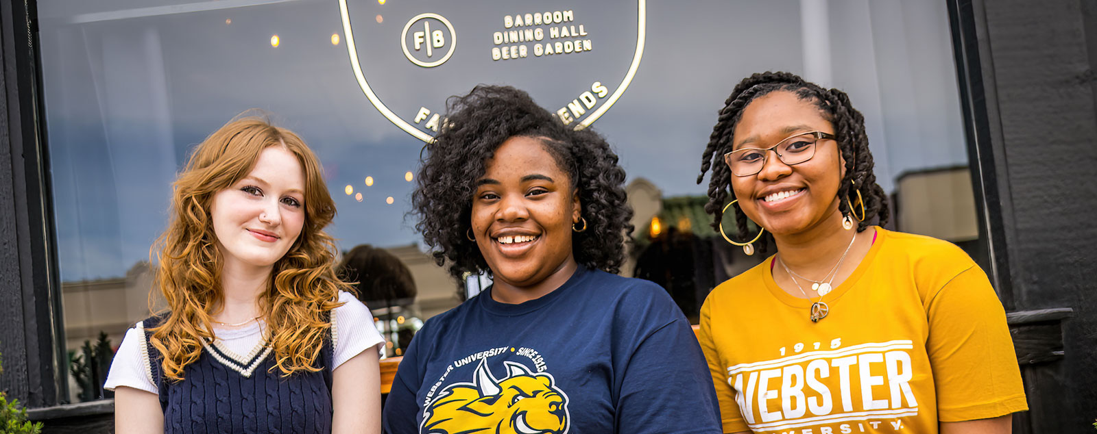 Students smiling in front of a local restaurant