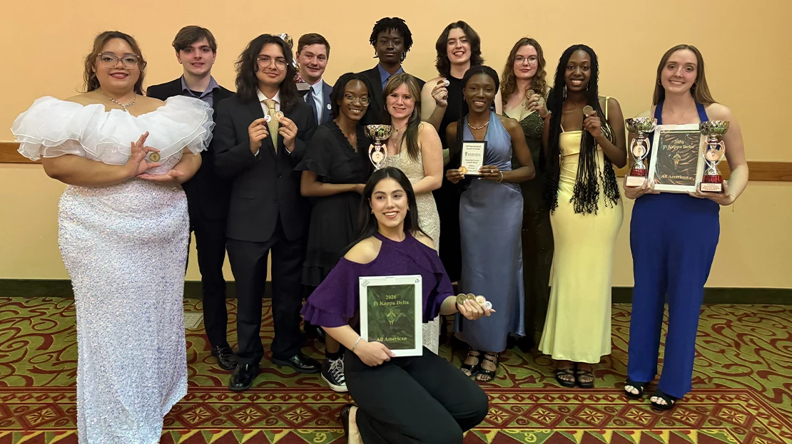A group of students holding their awards from the Forensics and Debate wins.