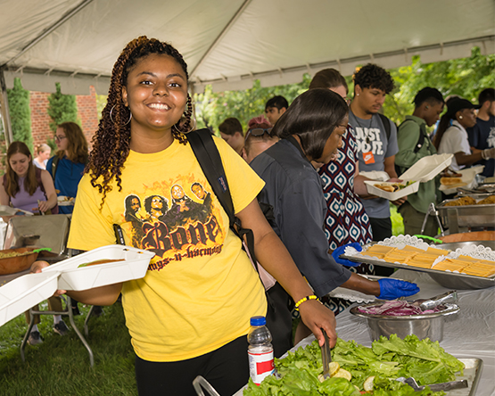 A student preparing a lunch at an outdoor event.