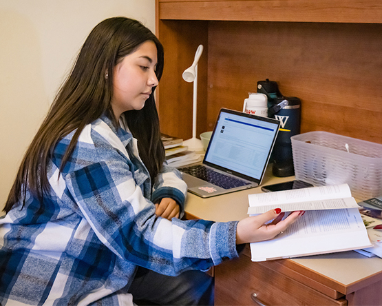 A resident student working at a desk in their dorm room.