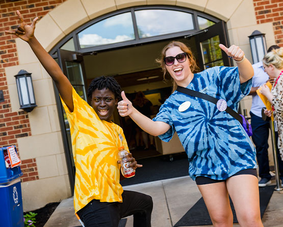 Two Webster students pose for a photo outside a campus residence hall.