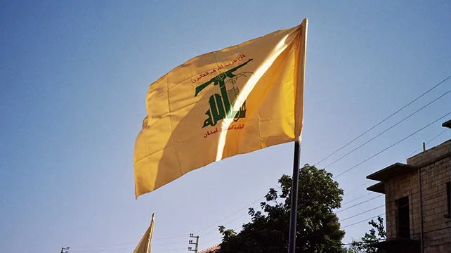 upyernoz from Wynnewood, PA, USA, , CC BY-SA 2.0 https://creativecommons.org/licenses/by-sa/2.0, via flickr yellow Hezbollah flag blowing in the wind
