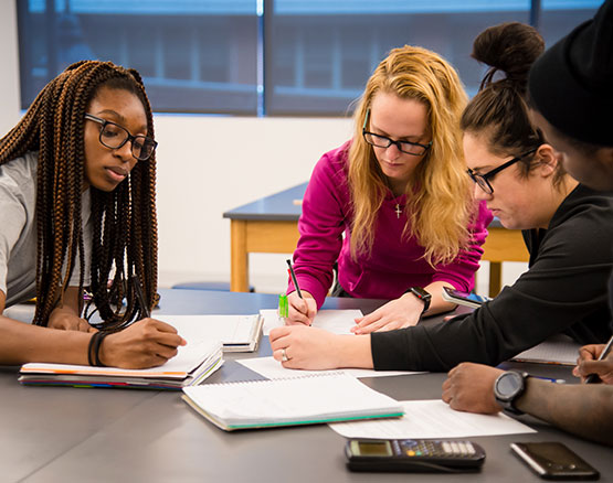 several students sitting at a lab table taking notes in class