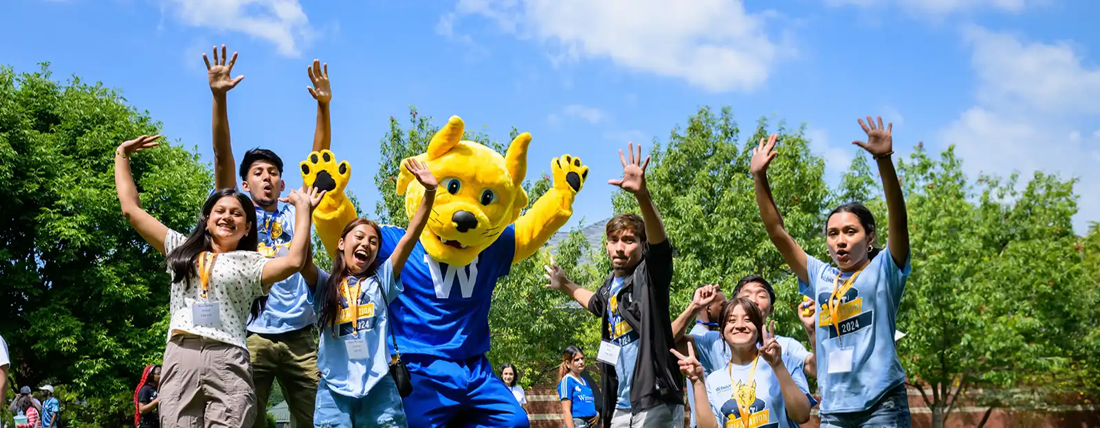 Gorlok and group of students wearing Webster T-shirts jumping in the air.