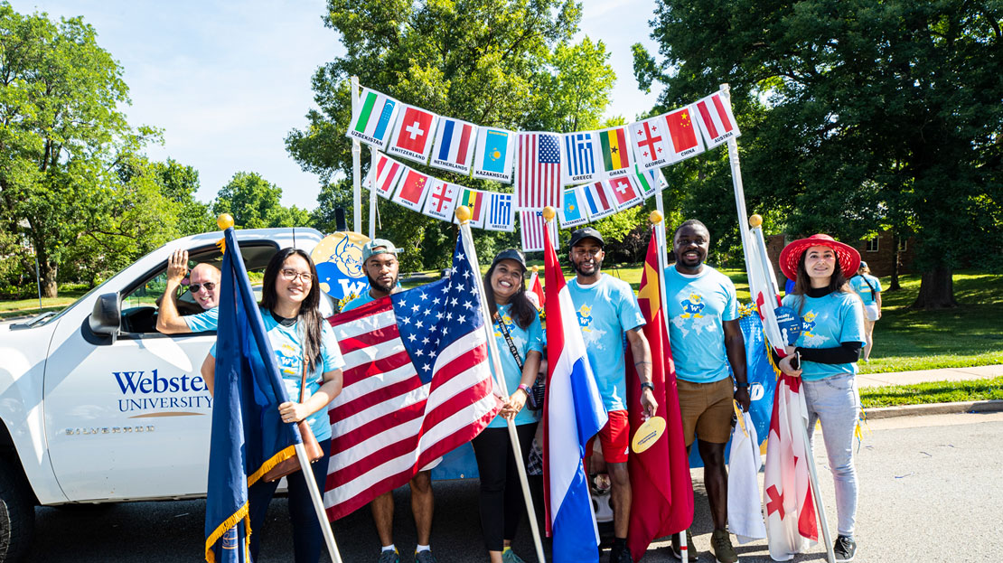 A group of students displaying flags of many nations at a parade.